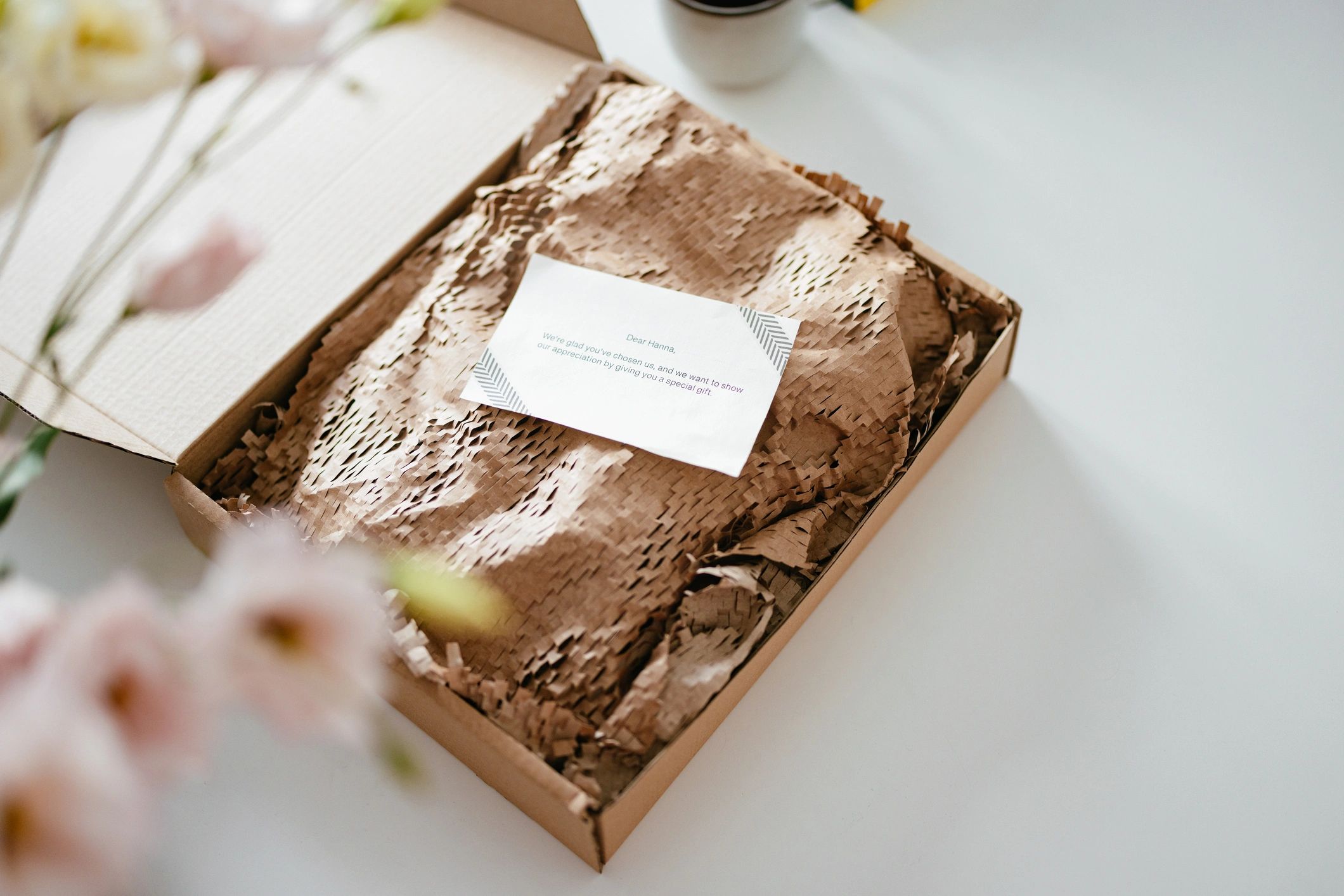 Open gift box with tissue paper and a note on top.