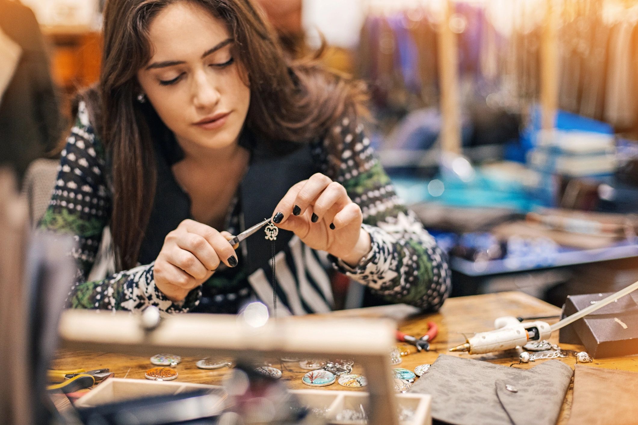Jewelry maker working at a studio workbench with tools and materials.